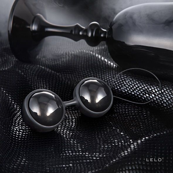 Boules de Geisha noires LELO posées sur tissu noir texturé