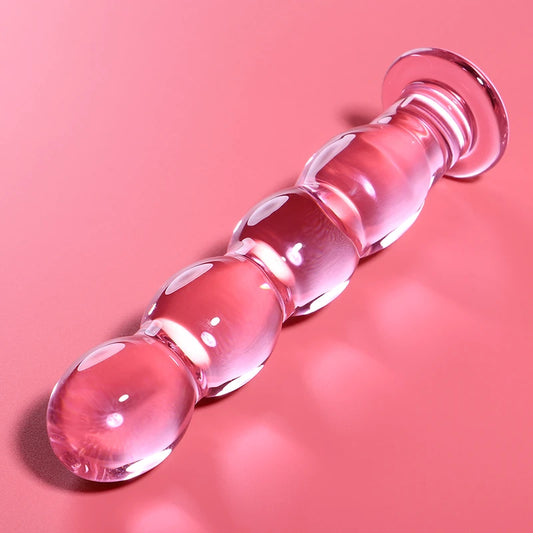Godemichet en verre rose avec segments arrondis et extrémité lisse posé sur fond rose