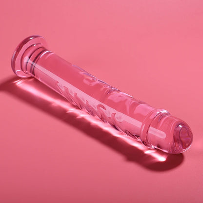 Godemichet en verre transparent rose avec forme droite et reliefs texturés posé sur fond rose