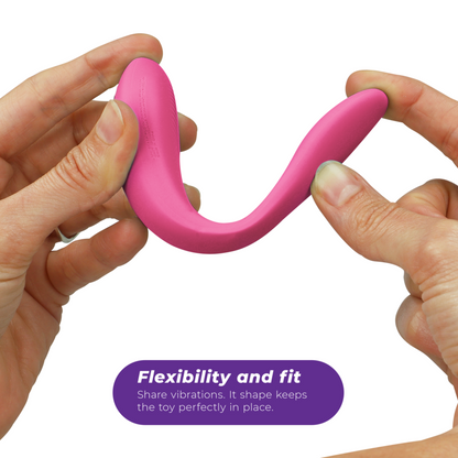 Vibromasseur couple rose en silicone tenu dans la main, vue montrant la taille compacte, la flexibilité et la forme en U