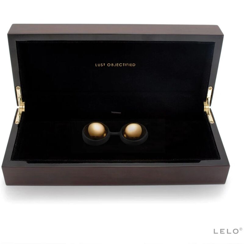 Coffret noir ouvert avec intérieur sombre contenant deux boules dorées