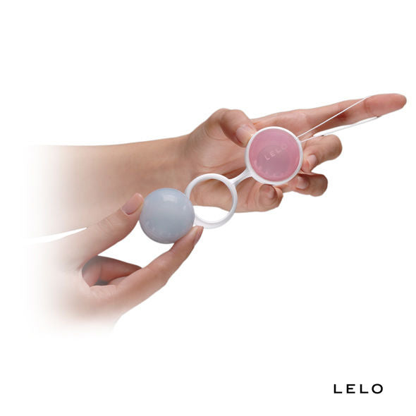 Main tenant deux boules de Geisha rose et bleu reliées par une tige blanche dont une enlevée de son anneau