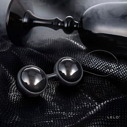 Boules de Geisha noires LELO posées sur tissu noir texturé