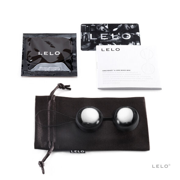 Boules argentées avec cordon noir, pochette noire et documentation posées sur fond clair